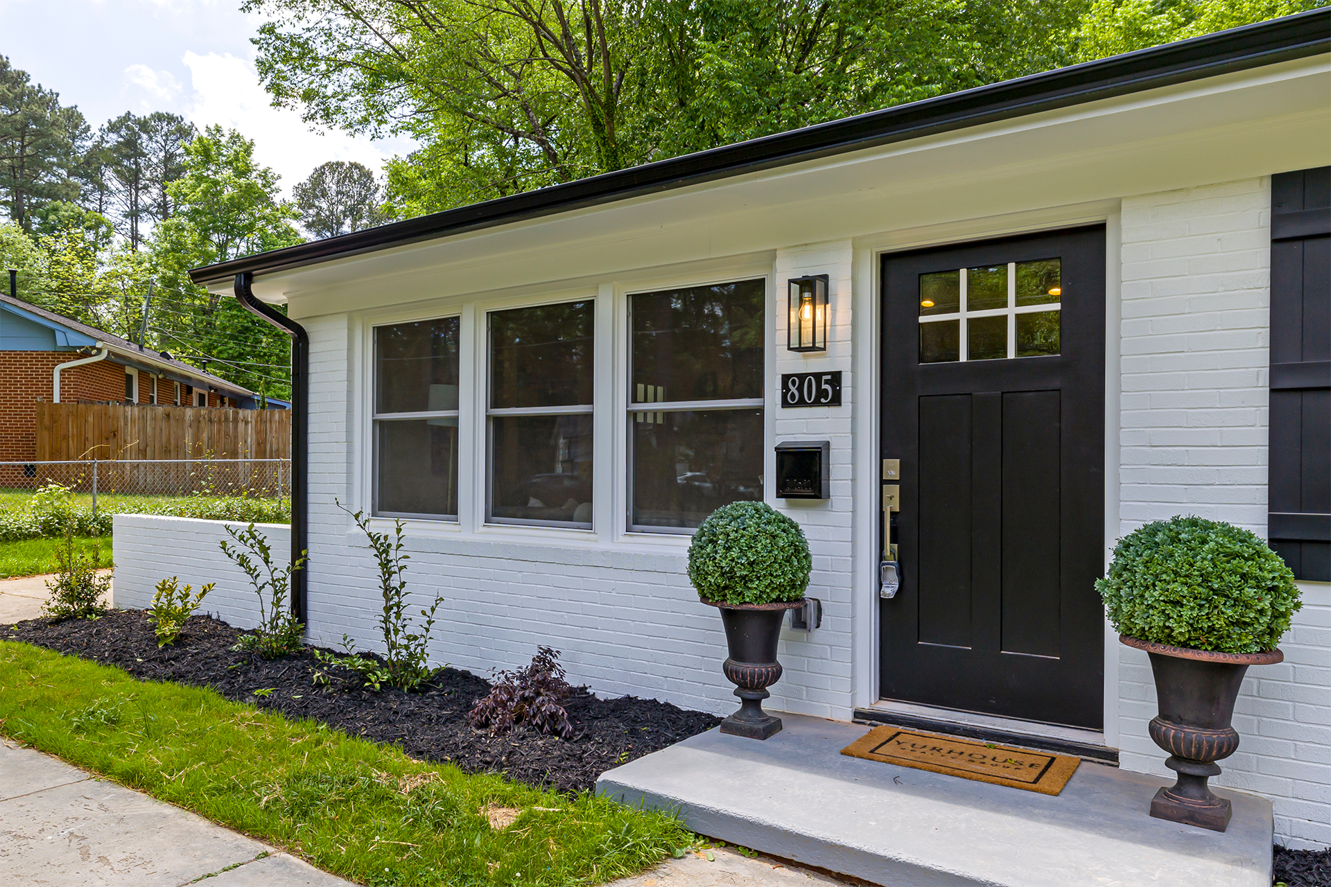 Small white house with a black front door and small garden.